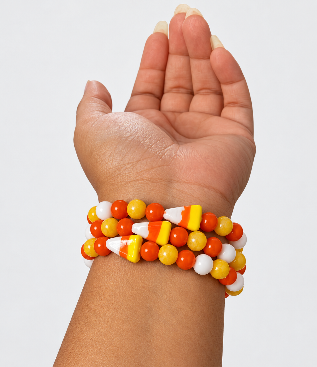 Candy corn bracelets stacked on a wrist, featuring yellow honey calcite, orange and white glass beads, and candy corn glass focal beads.