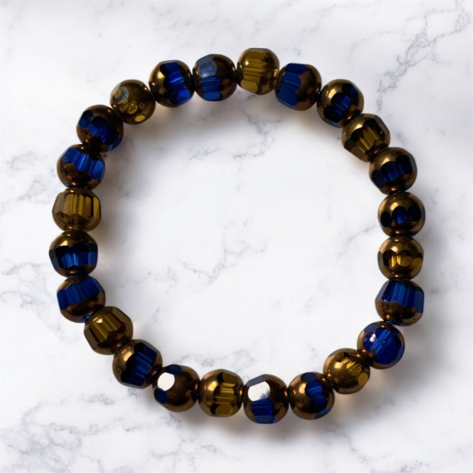 Blue and gold glass beaded bracelet and on a white surface by Divalicious Designs.