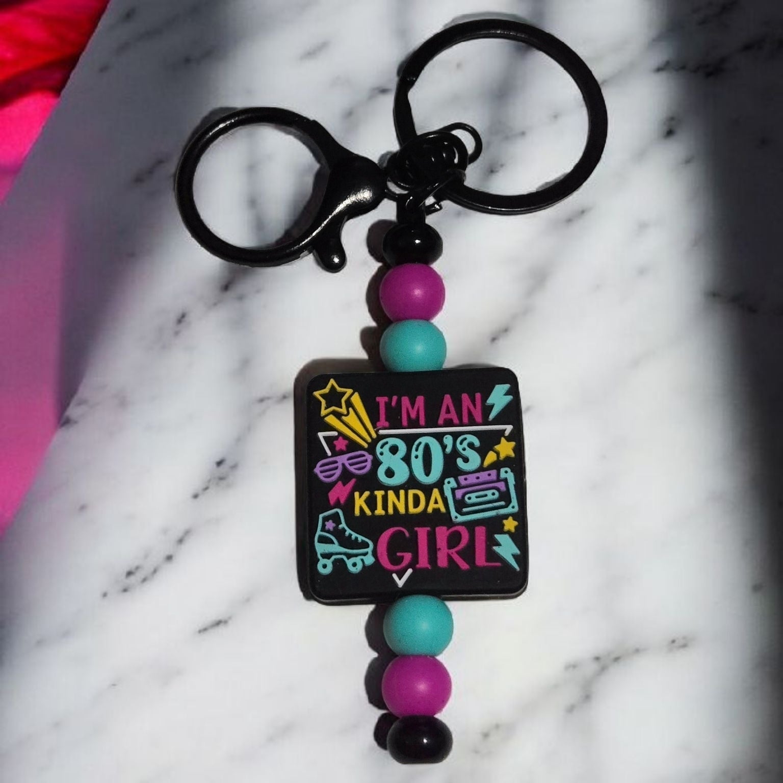 Keychain with colorful beads and 'I'm an 80s kinda girl' text on a marble surface