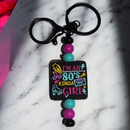 Keychain with colorful beads and 'I'm an 80s kinda girl' text on a marble surface