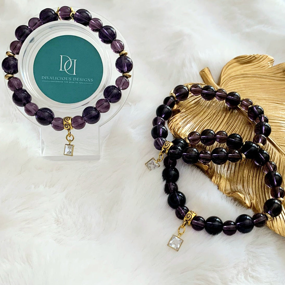 Amethyst coloured glass beaded bracelet with gold accents and a clear cubic zirconia charm. 
