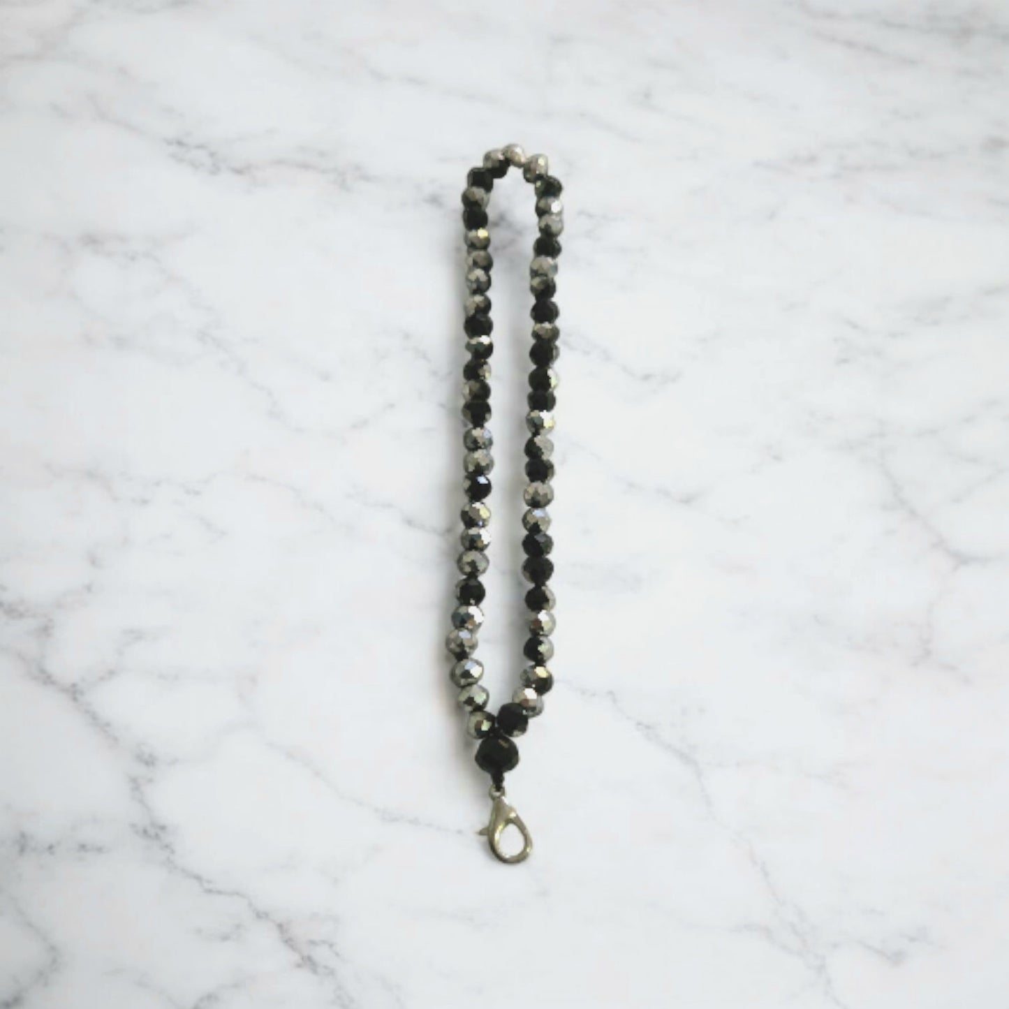 Black and SilverCrystal Beaded Phone Lanyard Strap  displayed on a light marble surface.