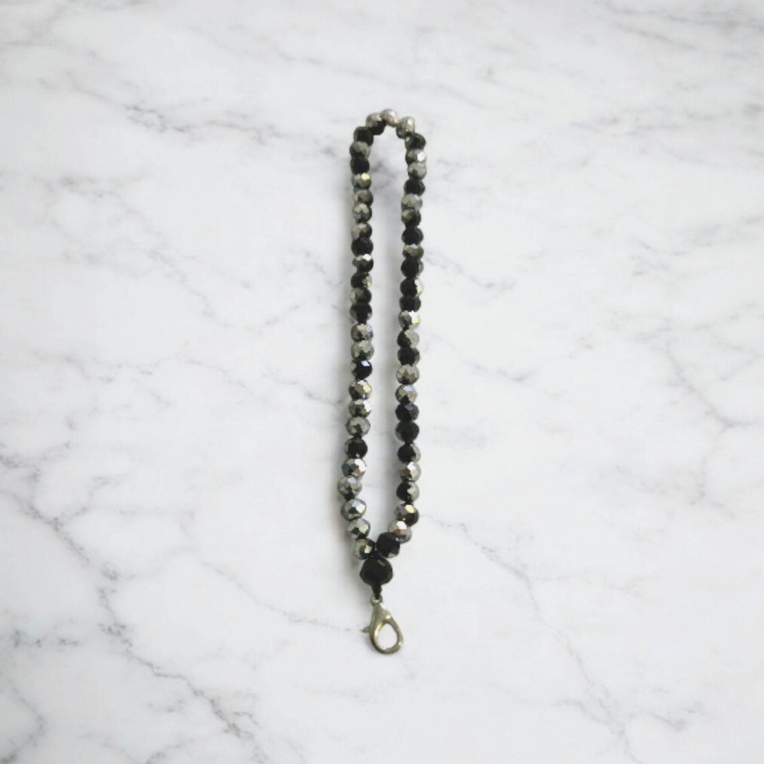 Black and SilverCrystal Beaded Phone Lanyard Strap  displayed on a light marble surface.