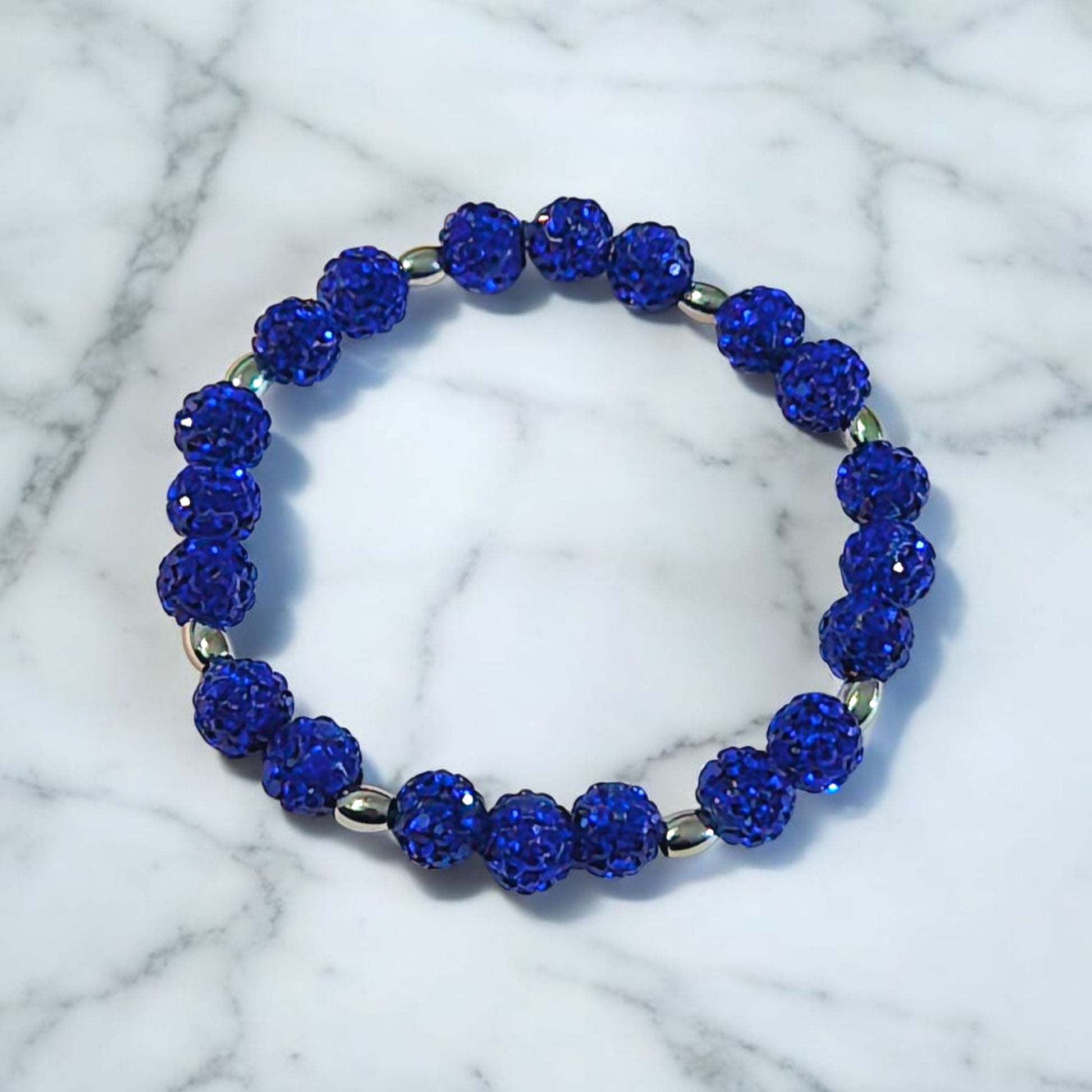 A Bracelet made of Royal Blue Shamballa beads and stainless steel beads laying on a marble surface. Picture and bracelet by Divalicious Designs.