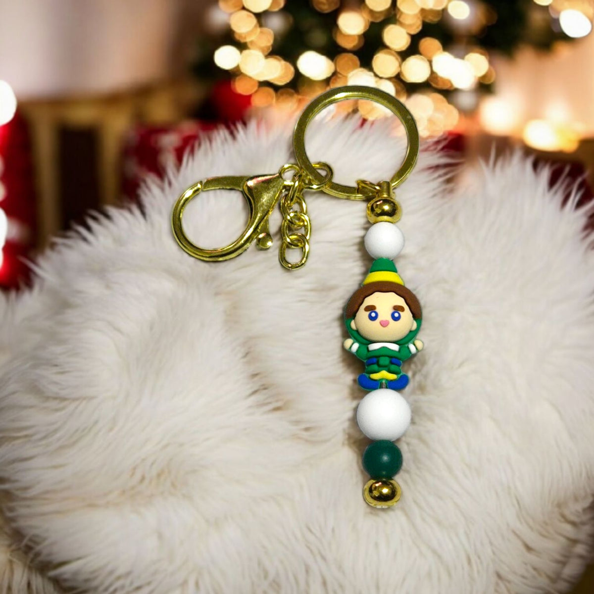 Keychain with Buddy the Elf on a fluffy surface with blurred festive lights in the background