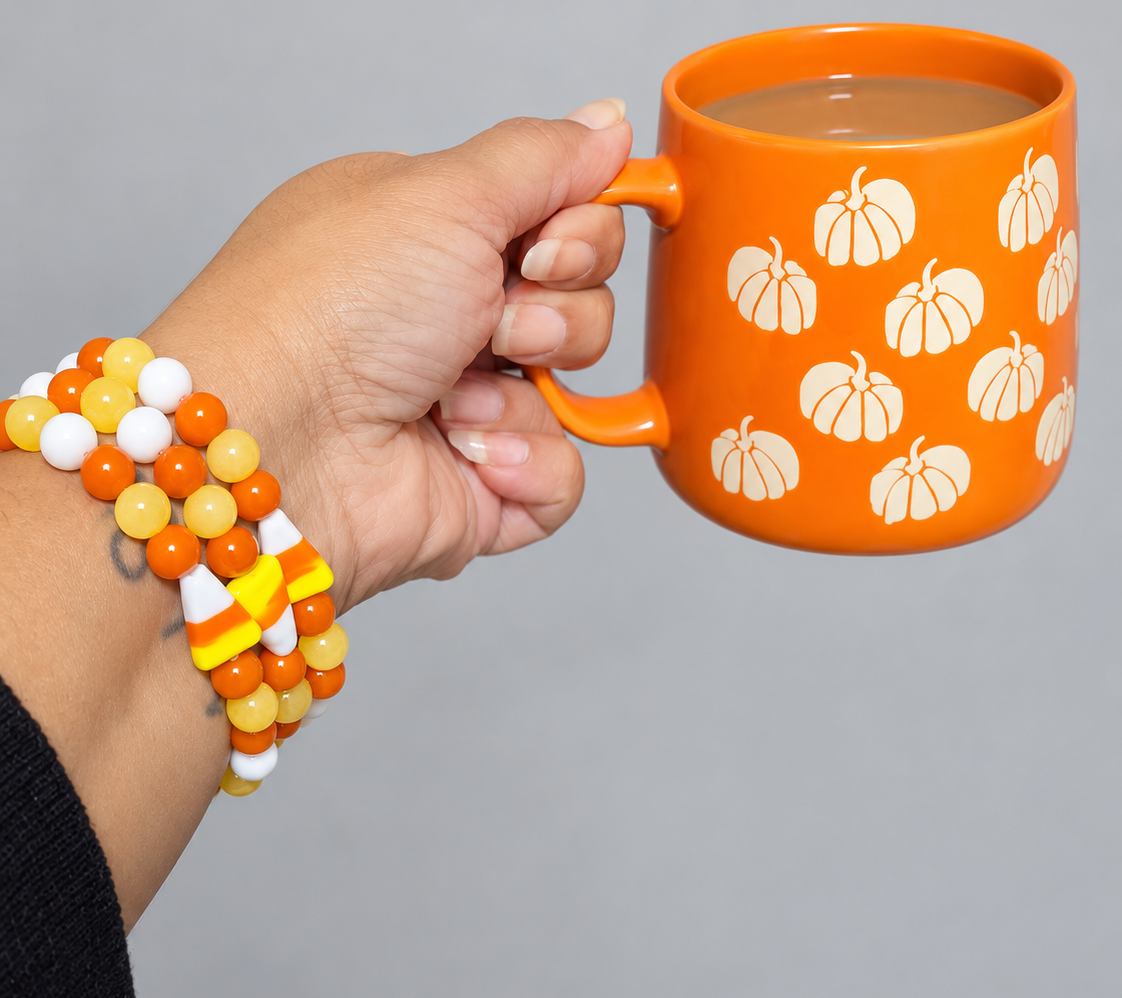 Candy corn bracelets stacked on a wrist, featuring yellow honey calcite, orange and white glass beads, and candy corn glass focal beads.