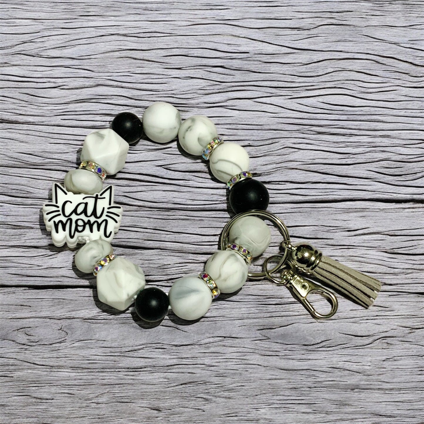 Beaded keychain wristlet with 'cat mom' focal bead a wooden surface.