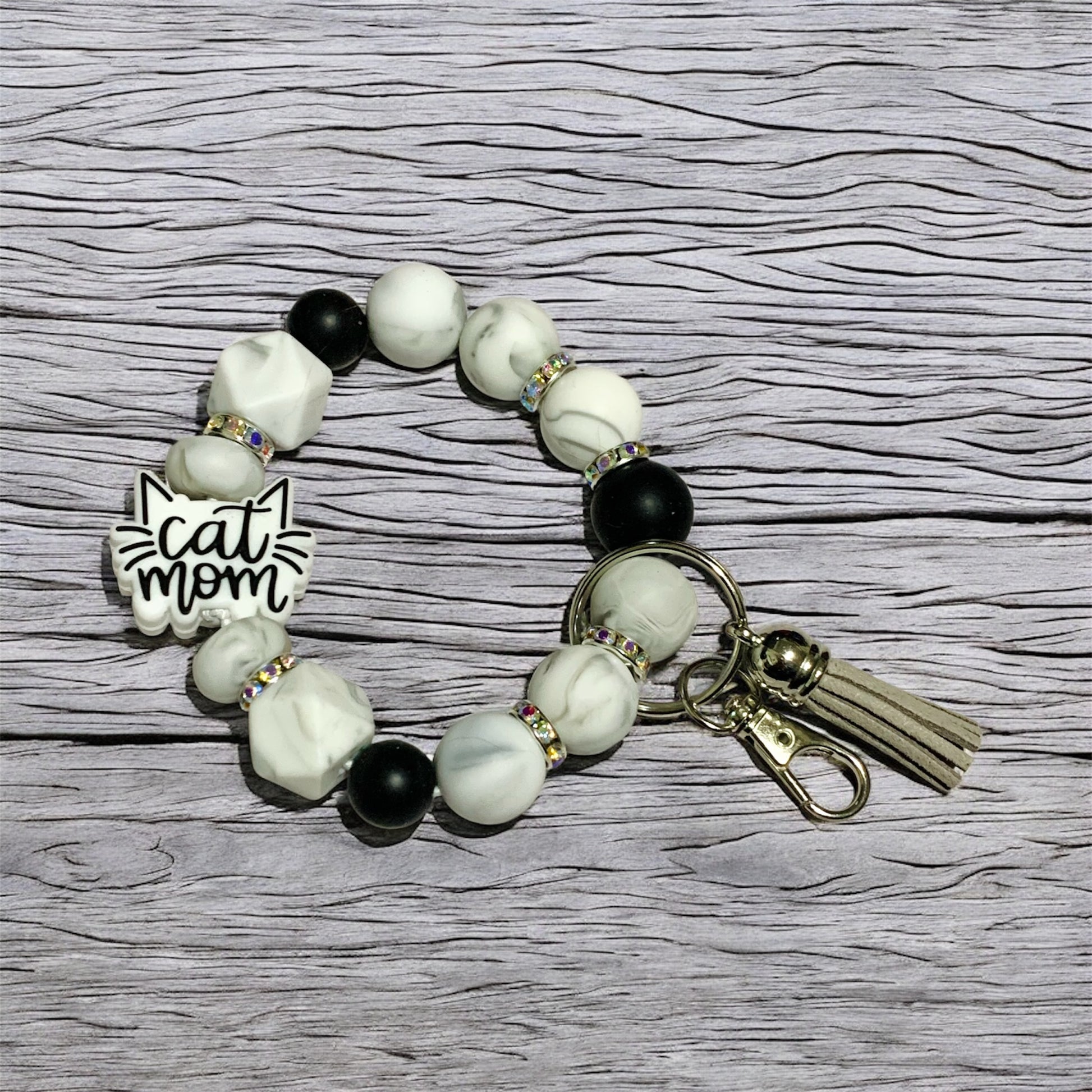 Beaded keychain wristlet with 'cat mom' focal bead a wooden surface.