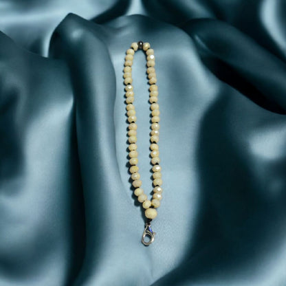 Cream coloured Crystal Beaded Phone Lanyard Strap displayed on a fabric surface.