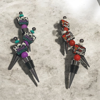 set of 6 sassy Wine Stoppers, hand made with food grade silicone beads and displayed on a concrete surface.