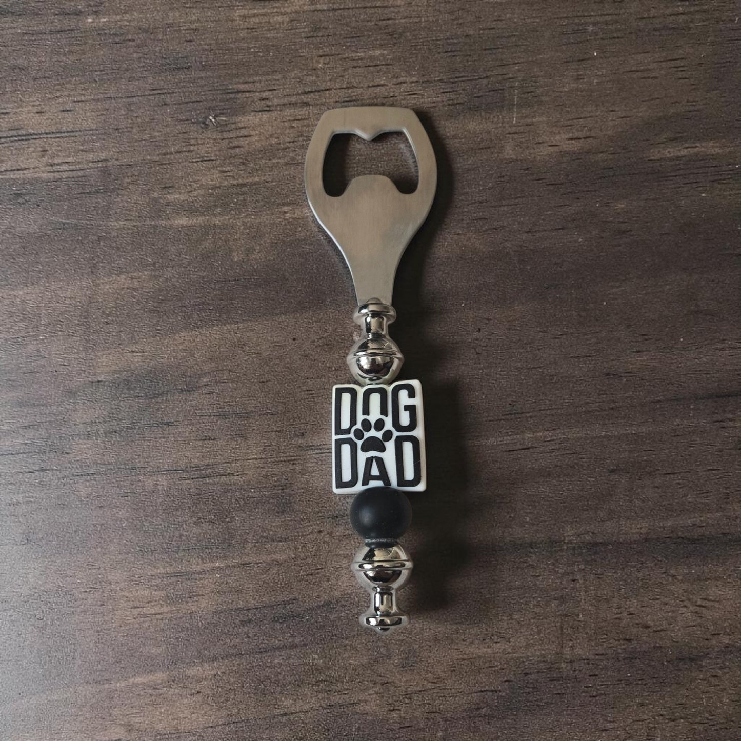 Steel and Silicone Bottle opener with 'Dog Dad' focal bead on a wooden surface.  Made by Divalicious Designs in Mississauga 