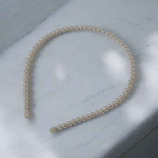 Pearl headband on a light gray surface, Photo and Headband by Divalicious Designs.