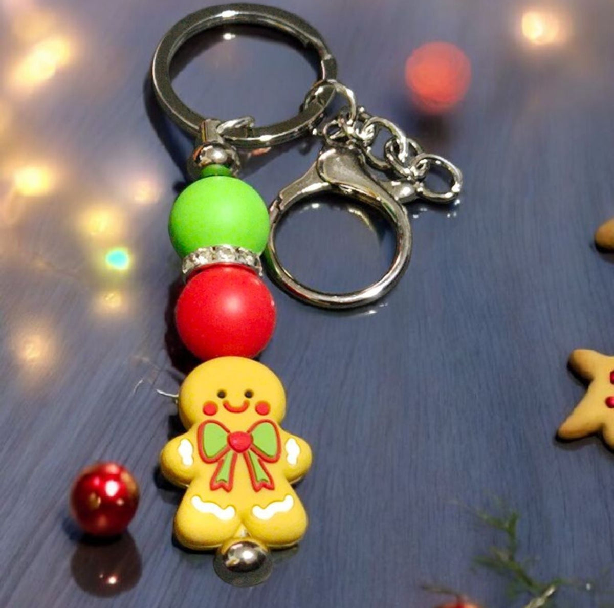 Keychain with gingerbread man design on a reflective surface with blurred lights in the background