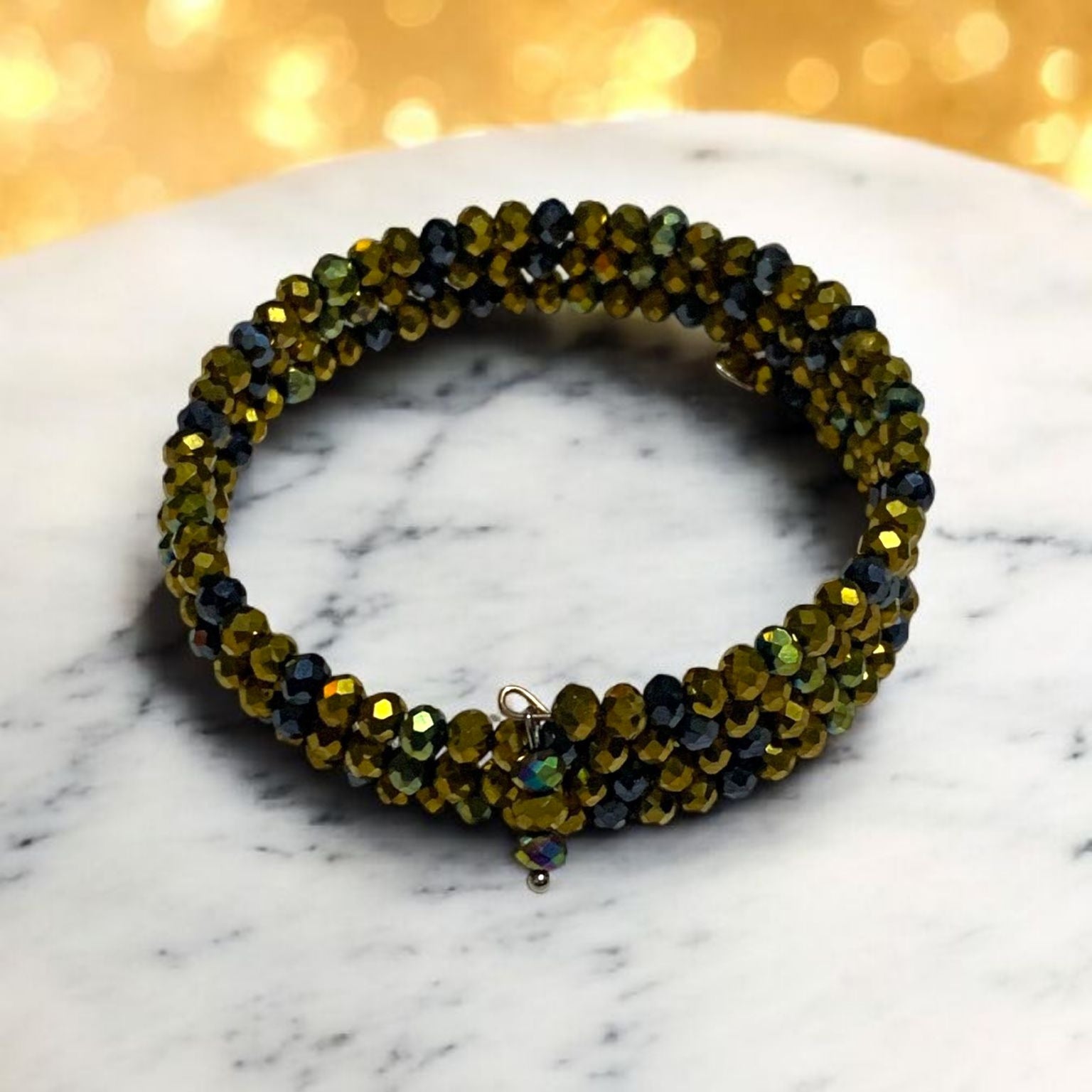 Beaded  vrystal bracelet on a marble surface with a gold glittery background. Bracelet is made of memory wire and made by Divalicious Designs.