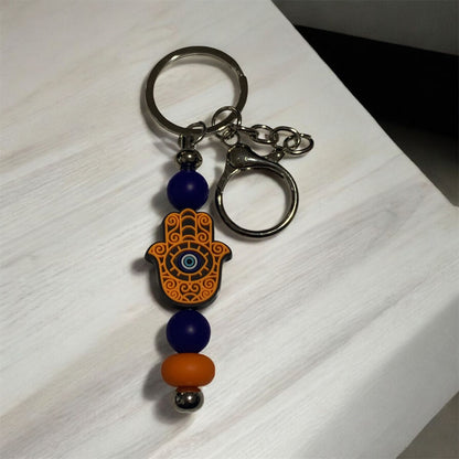 Keychain with Hamsa hand design and beads on a light wooden surface