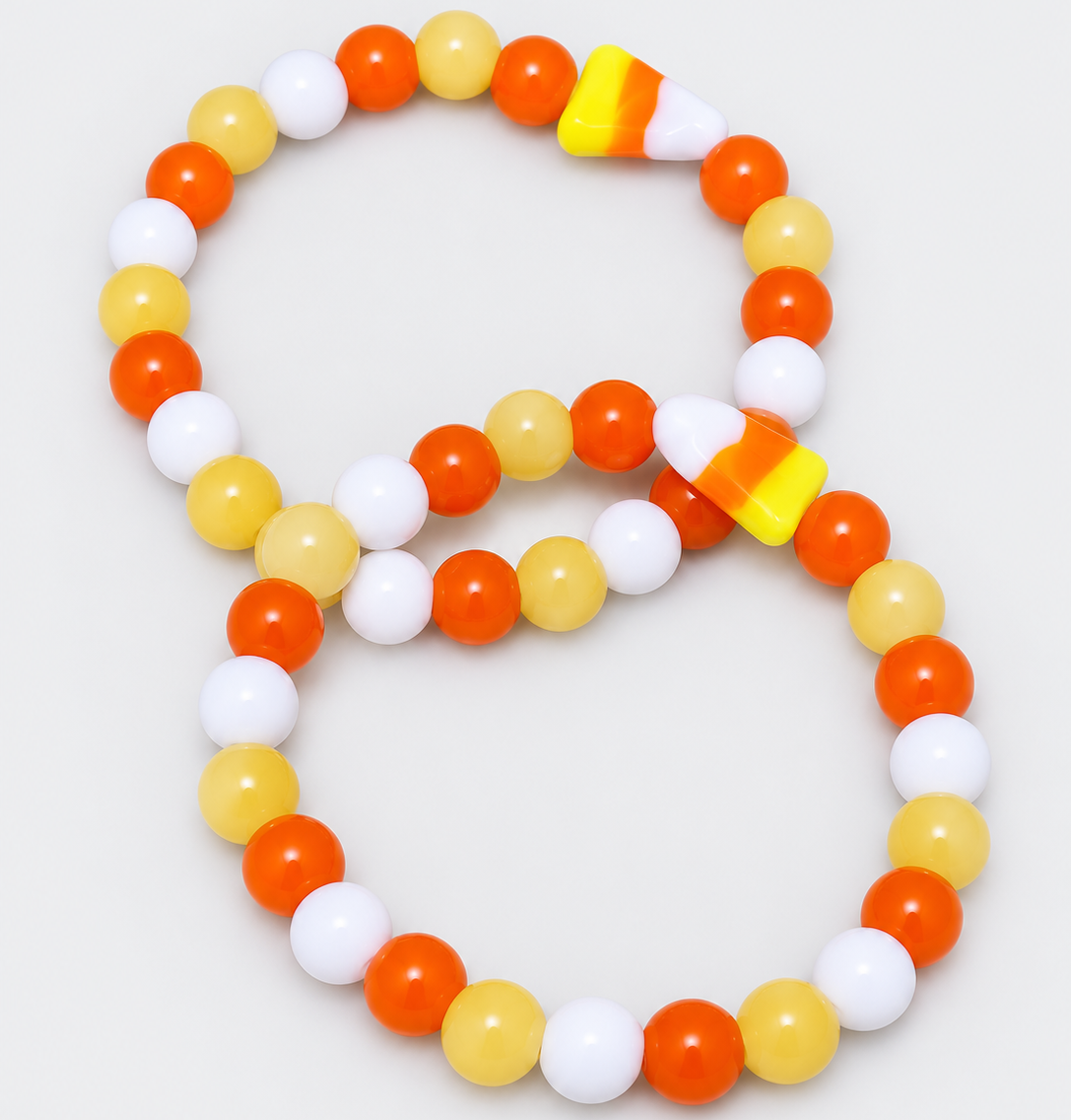 Two candy corn bracelets with yellow honey calcite, orange and white glass beads, and candy corn glass focal beads on a light grey background.