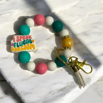 Colorful beaded keychain with 'I speak fluent sarcasm' tag on a marble surface