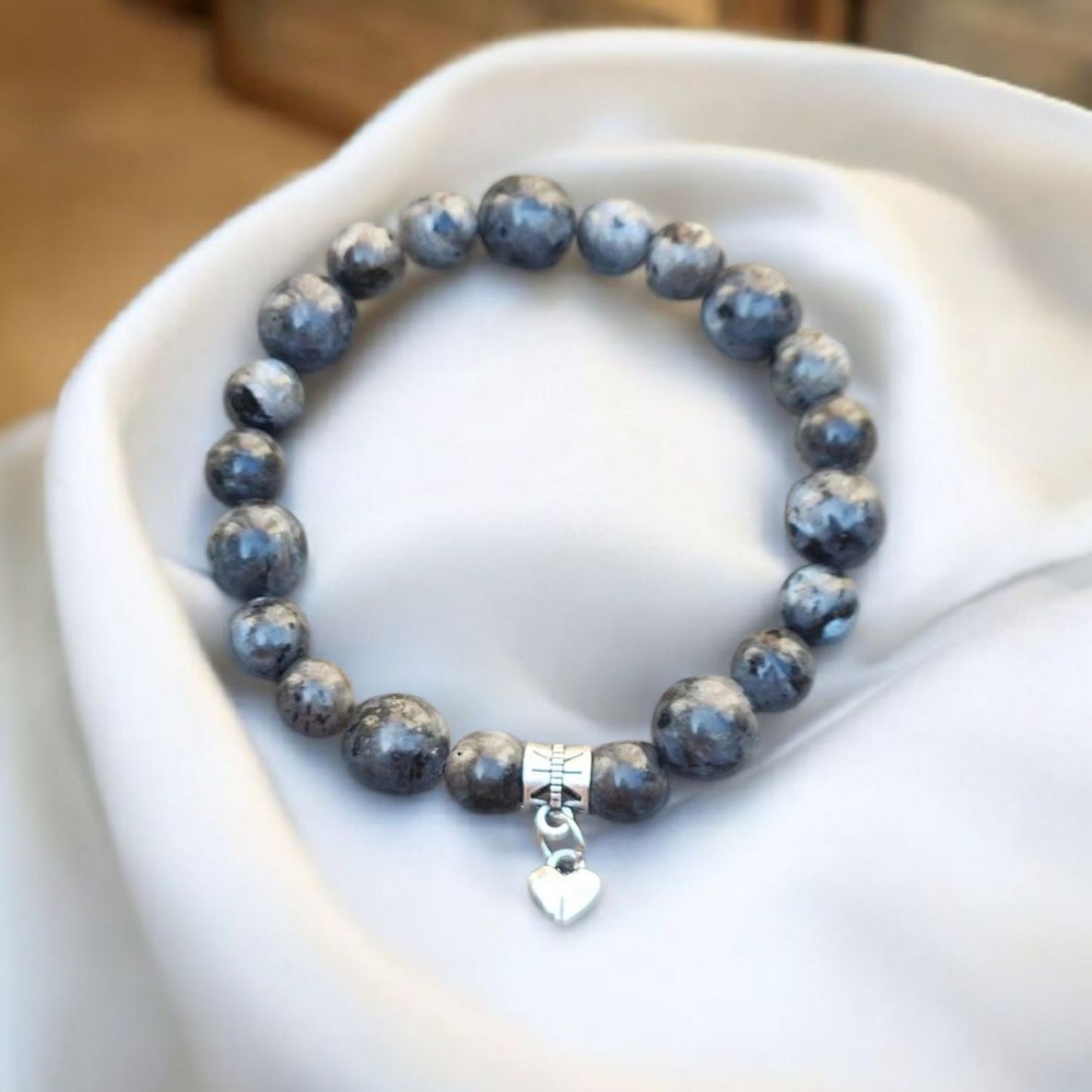 8mm and 10mm beaded Labradorite bracelet with a silver heart charm on a white surface. Photo and Bracelet by Divalicious Designs