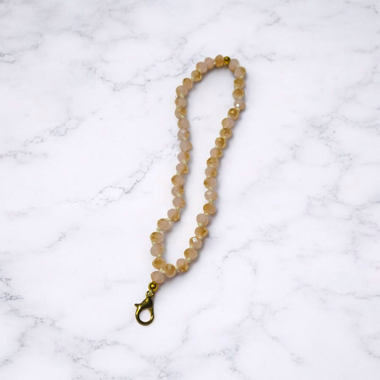 Light Pink and a gold Crystal Beaded Phone Lanyard Strap  displayed on a light marble surface.