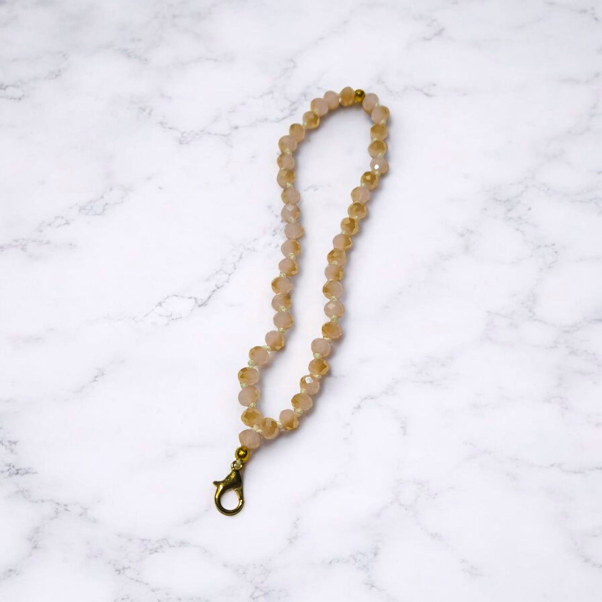 Light Pink and a gold Crystal Beaded Phone Lanyard Strap  displayed on a light marble surface.