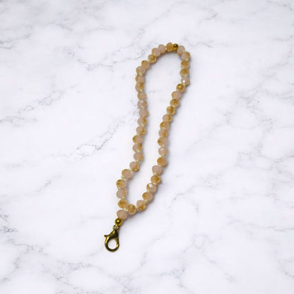 Light Pink and a gold Crystal Beaded Phone Lanyard Strap  displayed on a light marble surface.