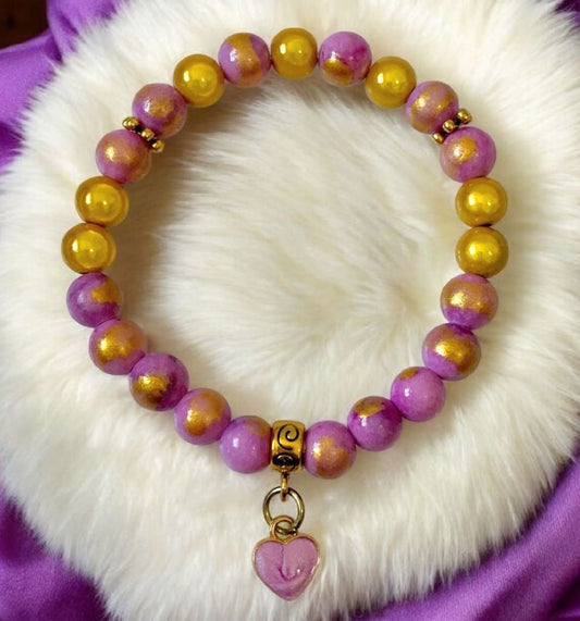 Handmade lilac and gold beaded bracelet with a purple heart charm displayed on a soft white background