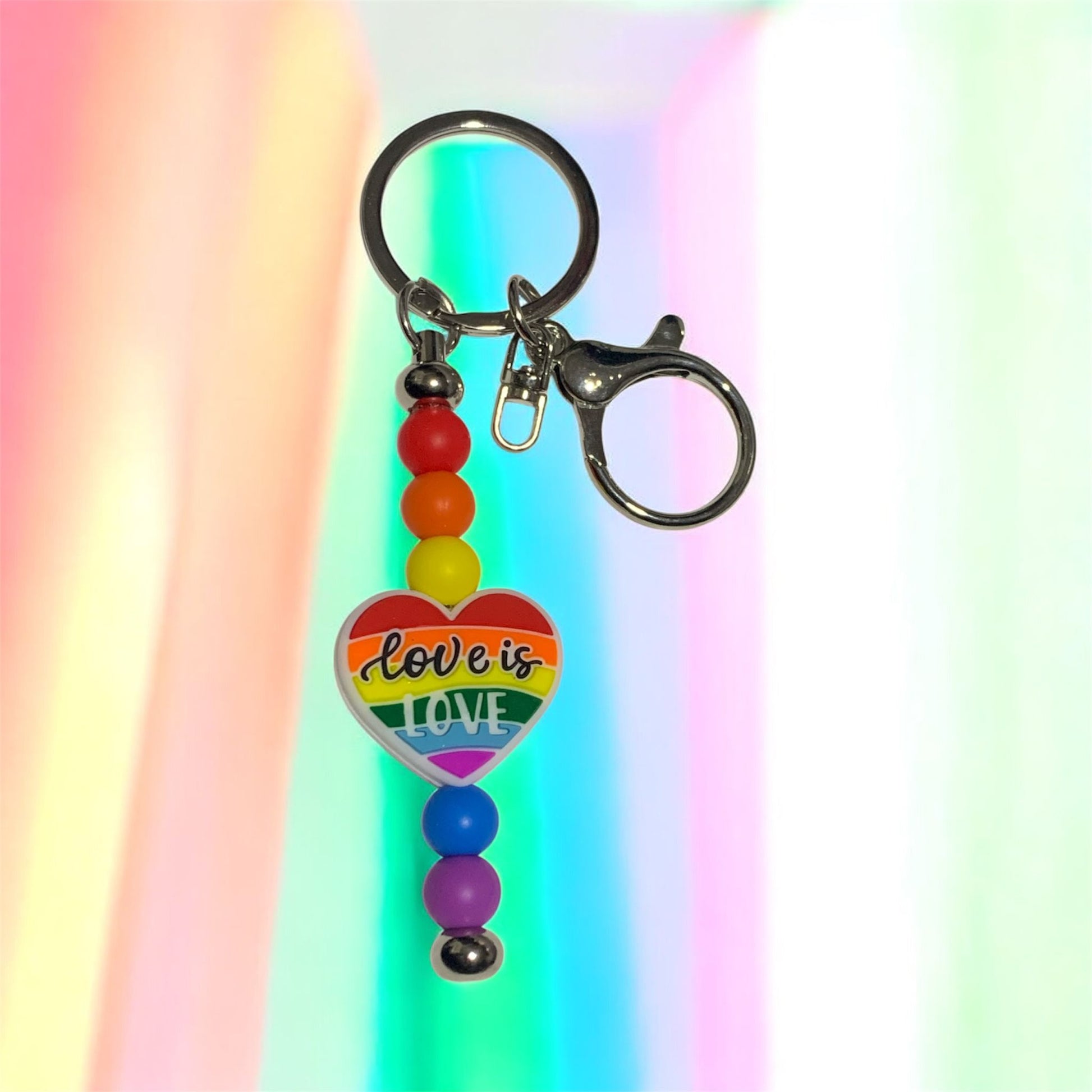 Keychain with rainbow beads and 'Love is Love' heart charm on a colorful background