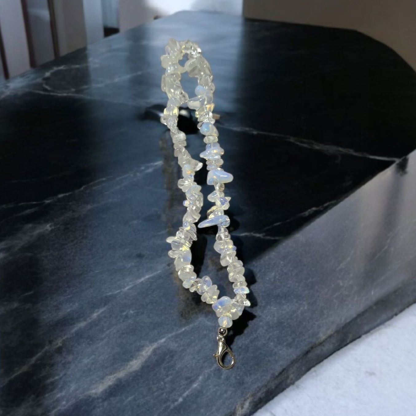 A phone lanyard made of Opalite stone chip beads displayed on a dark marble surface.  Photo and lanyard made by Divalicious Designs.
