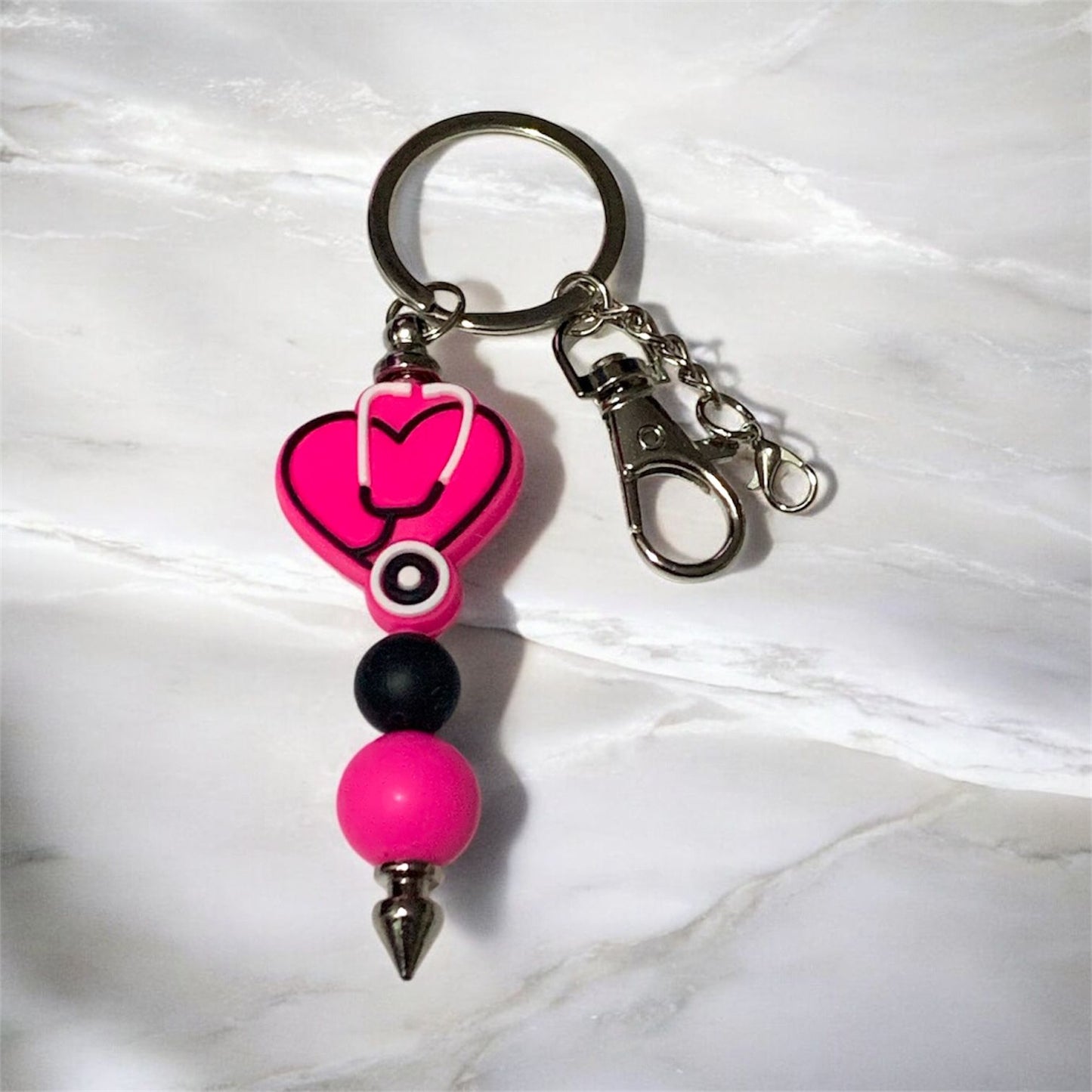 Pink Heart with Stethoscope Silicone Keychain on a White Marble background.