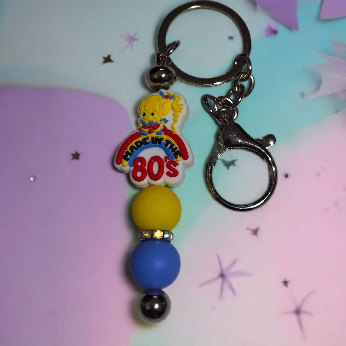 Keychain with Rainbow Brite cartoon character and colorful beads on a pastel background. The Focal bead states, "Made in the 80's".