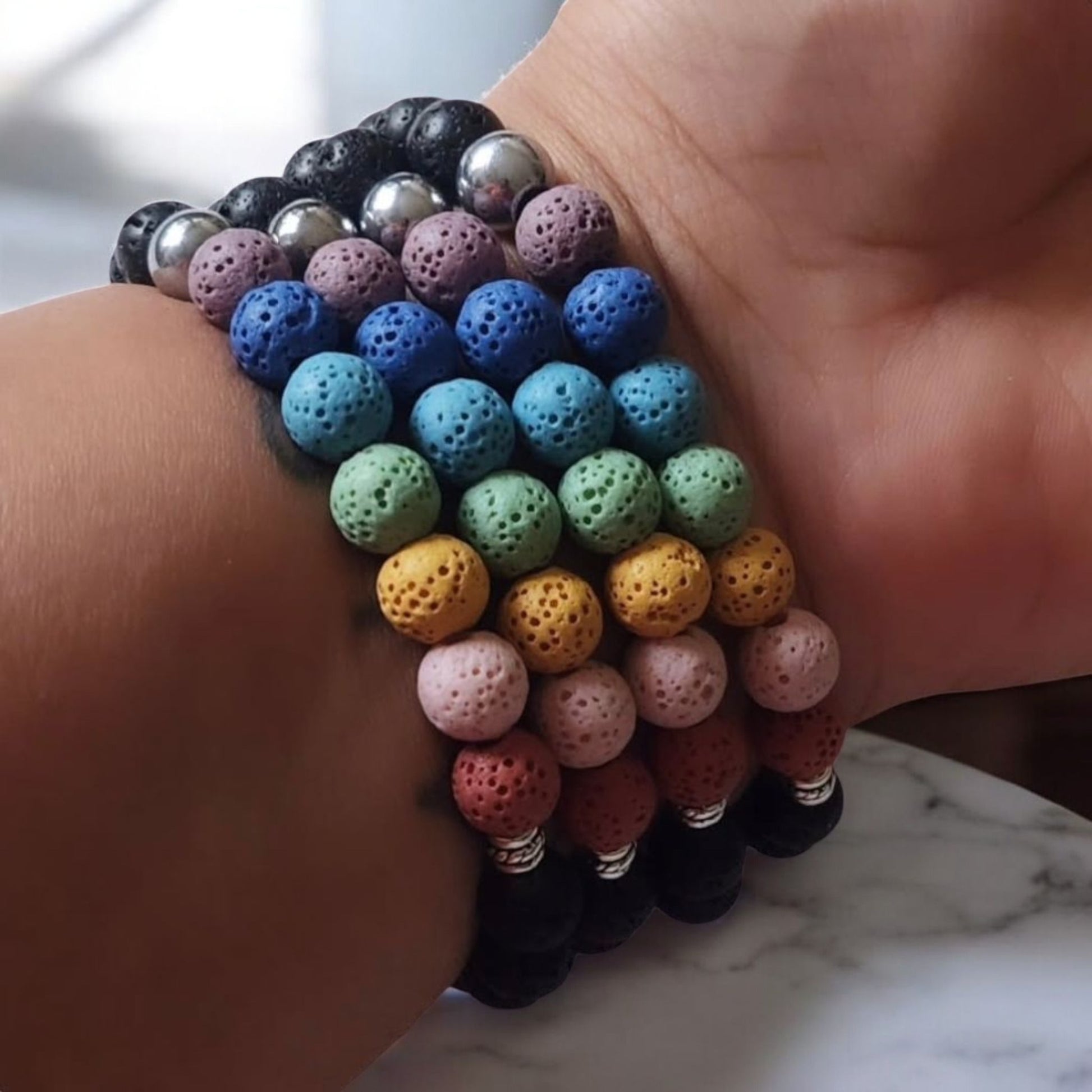 Reiki bracelets made with lava beads stacked on a wrist.
