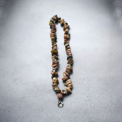 A phone lanyard made of Rhodonite stone chip beads displayed on a light marble surface.  Photo and lanyard made by Divalicious Designs.