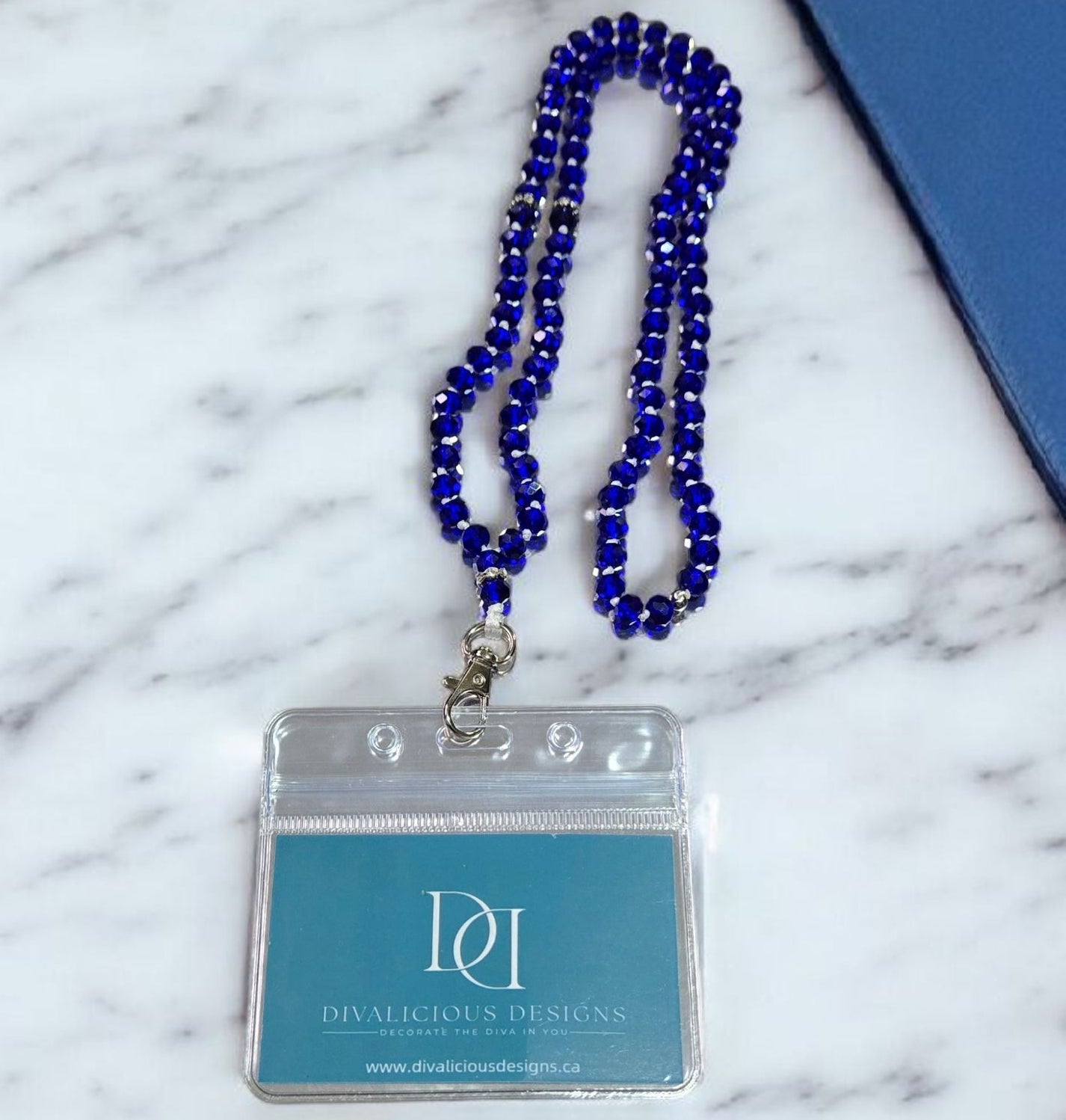 Handmade blue glam crystal ID lanyard necklace with clear badge holder displayed on white desk