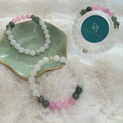 White chalcedony bracelets with pink kunzite, moss agate beads, rhinestone spacers, and a gold cage bead displayed on a white fur surface.