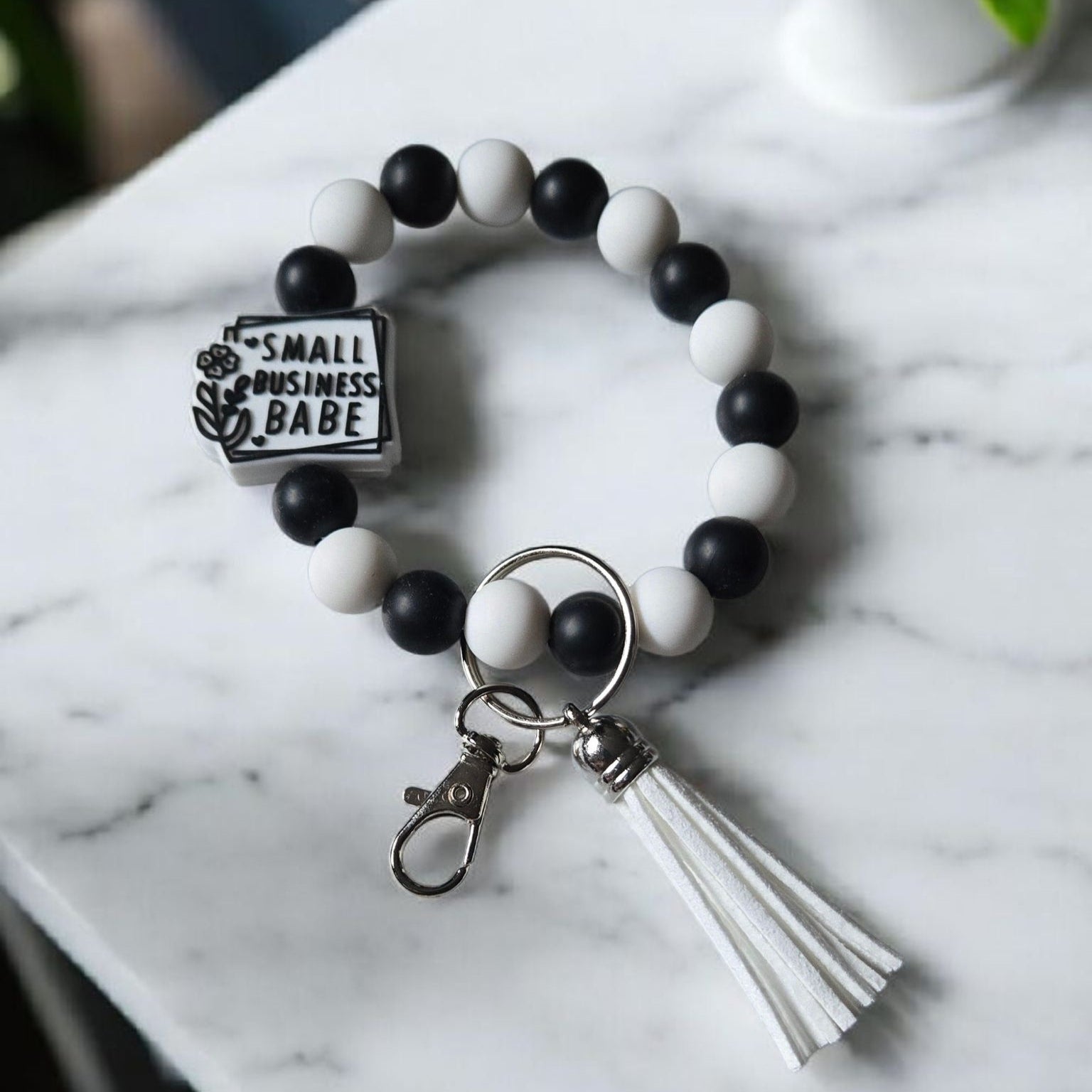 Black and white Silicone beaded keychain bracelet with a focal bead stating "Small Business Babe". The product is displayed on a light marble counter.