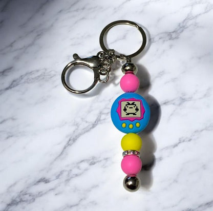 Tamagotchi Silicone Beaded Keychain on a marbled surface.