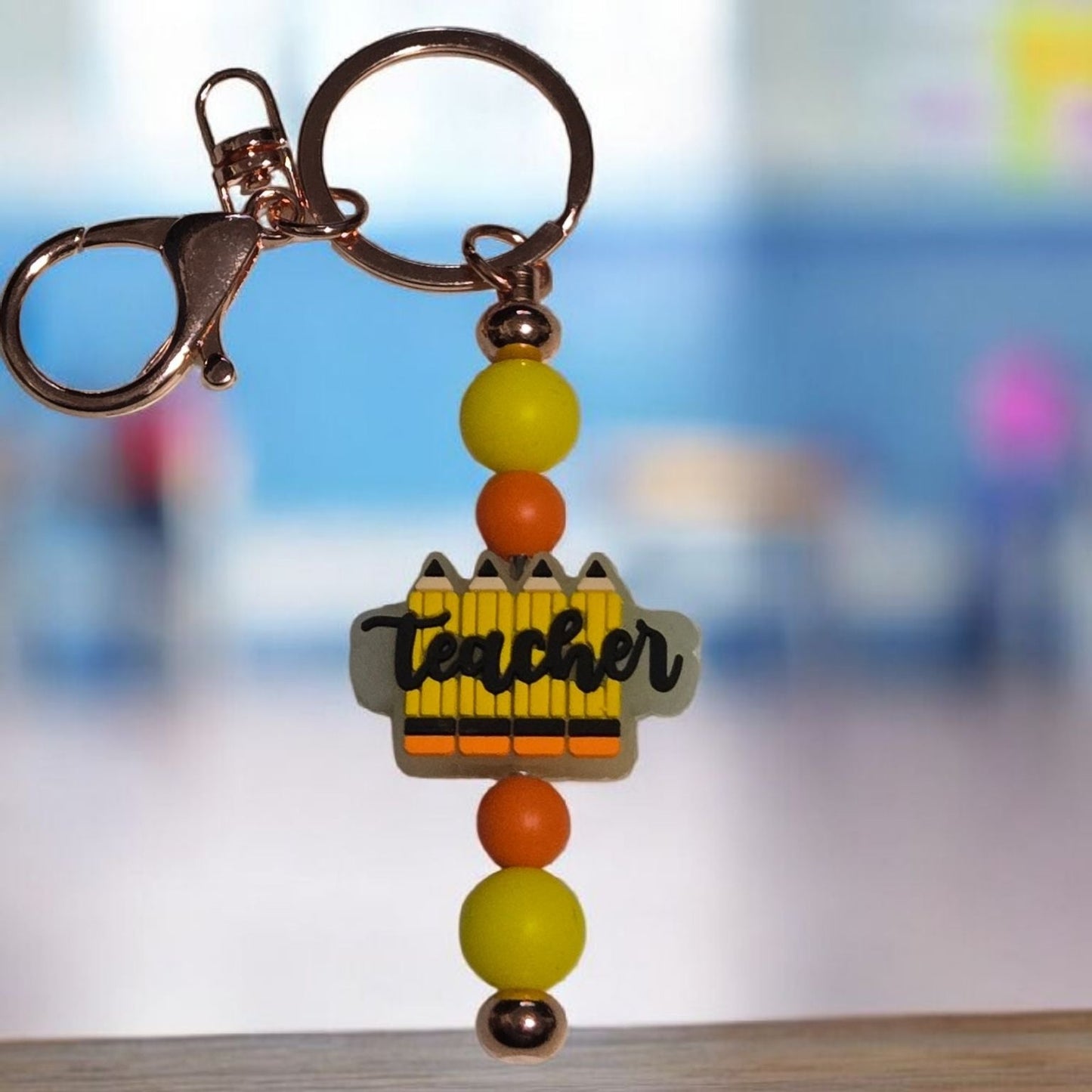 Keychain with beads and 'Teacher' charm on a blurred background