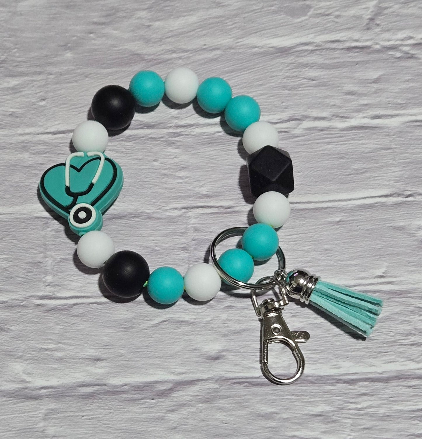 Beaded keychain with teal heat and Stethoscope focal bead ona textured surface