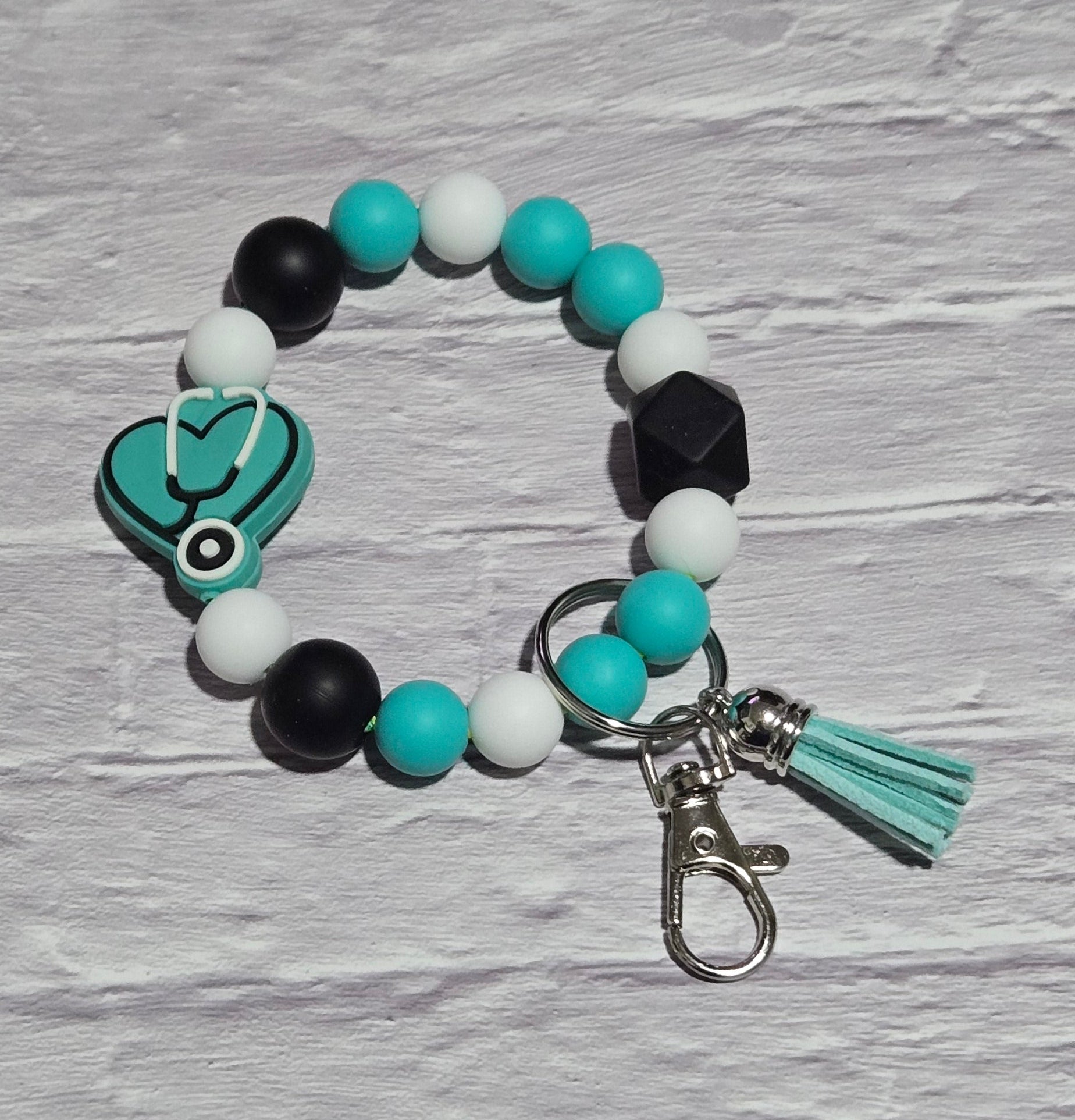 Beaded keychain with teal heat and Stethoscope focal bead ona textured surface