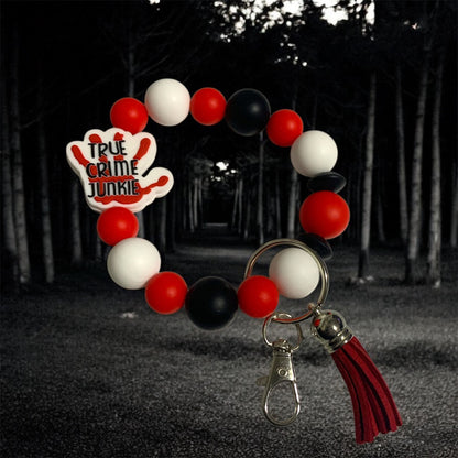 Keychain with red, white, and black balloons and 'True Crime Junkie' logo against a dark forest background.