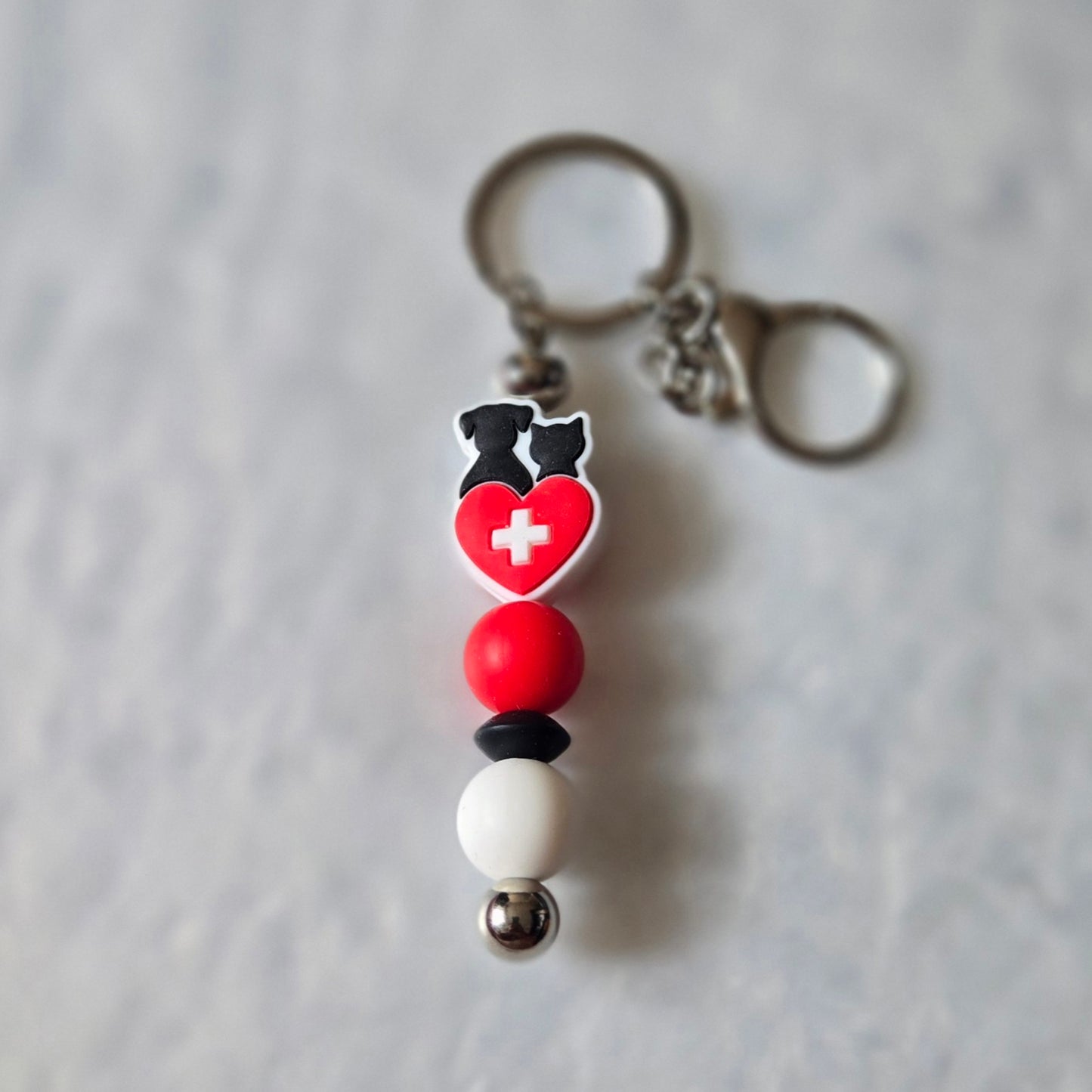 Keychain with heart and cross design on a gray background