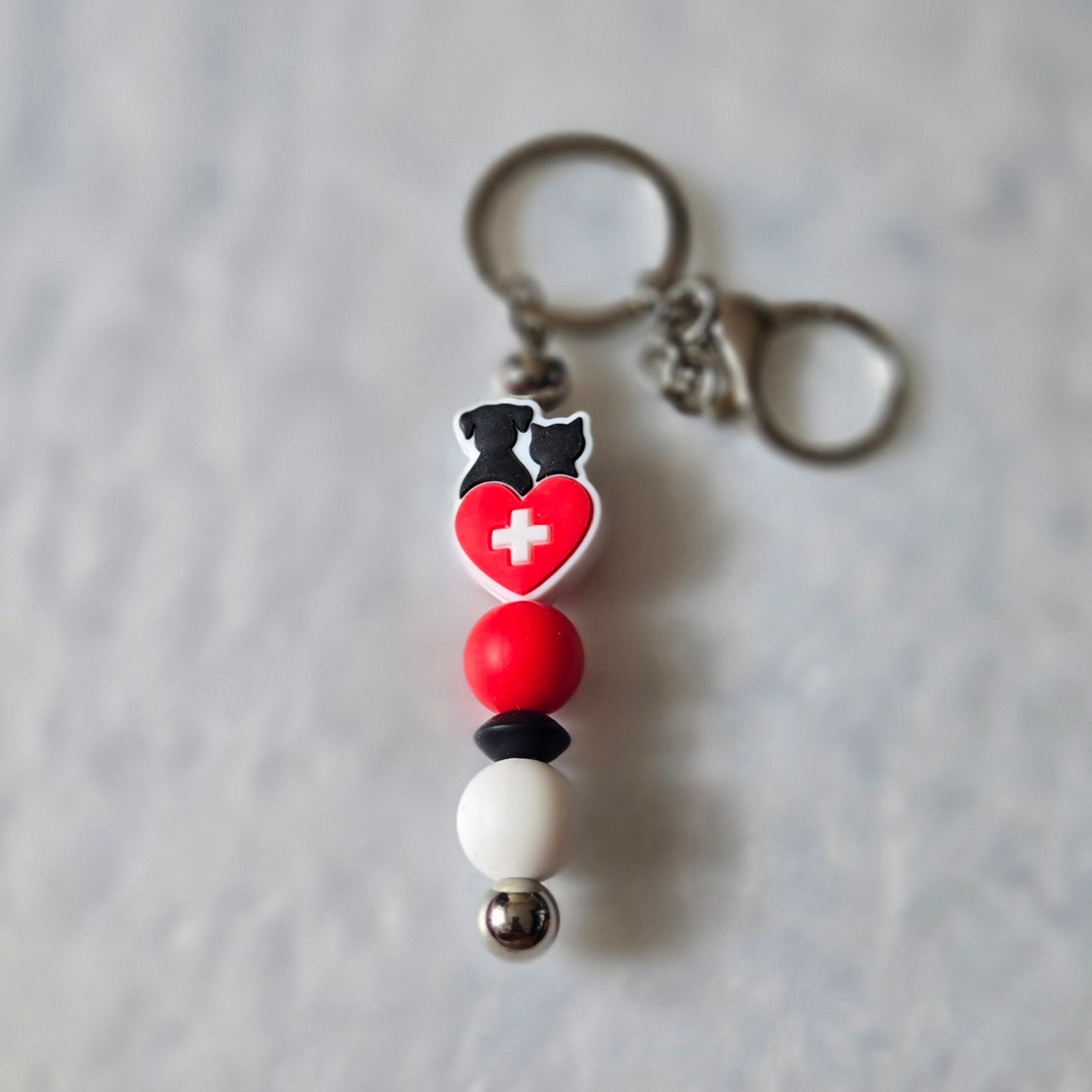Keychain with heart and cross design on a gray background