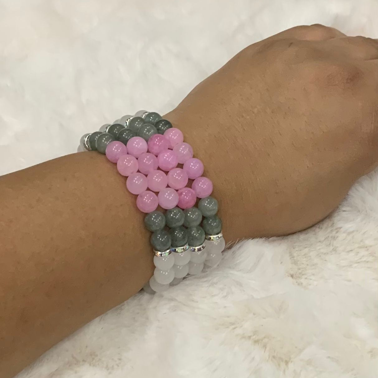 Beaded bracelet with pink, gray, and white beads on a wrist against a white background