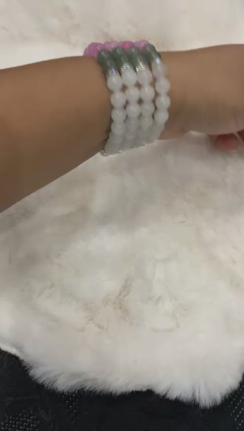 Blush and Ice Chalcedony Bracelets being displayed on a wrist over a white fur surface.
