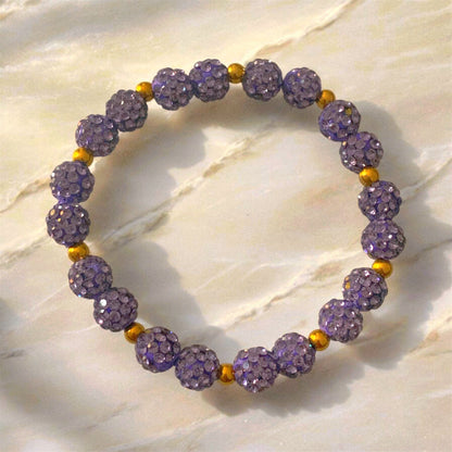 A Bracelet made of Lilac Shamballa beads and golden coloured stainless steel beads laying on a marble surface. Picture and bracelet by Divalicious Designs.