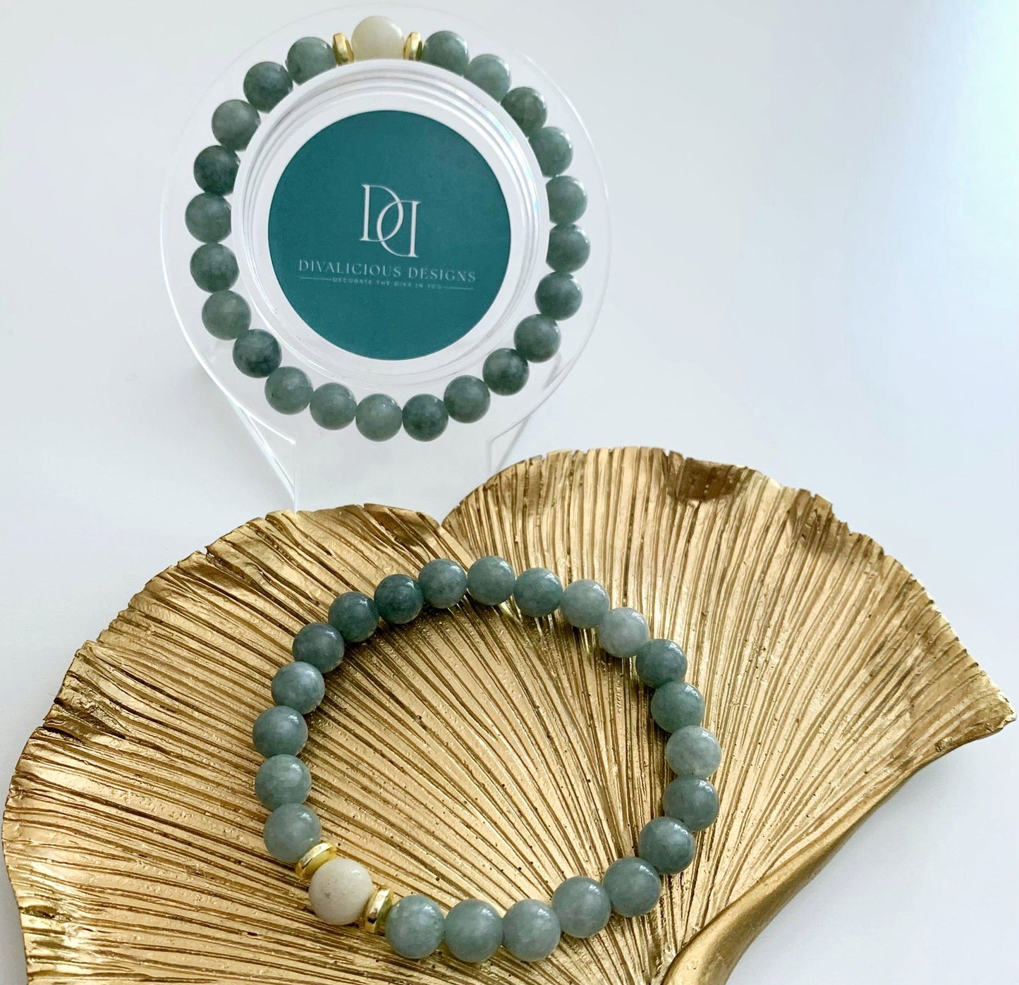 Burmese jade bracelet with a pale amazonite focal bead and gold-plated hematite accents displayed beside a gold decorative dish.